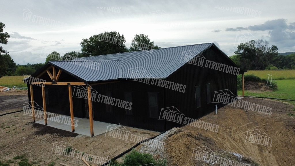 Black barndominium construction with a porch and concrete foundation by Rohlin Structures in Missouri.