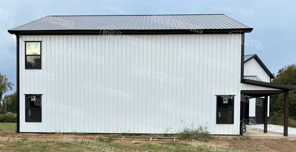 Completed Heritage barndominium with white siding, black trim, and wraparound porch.