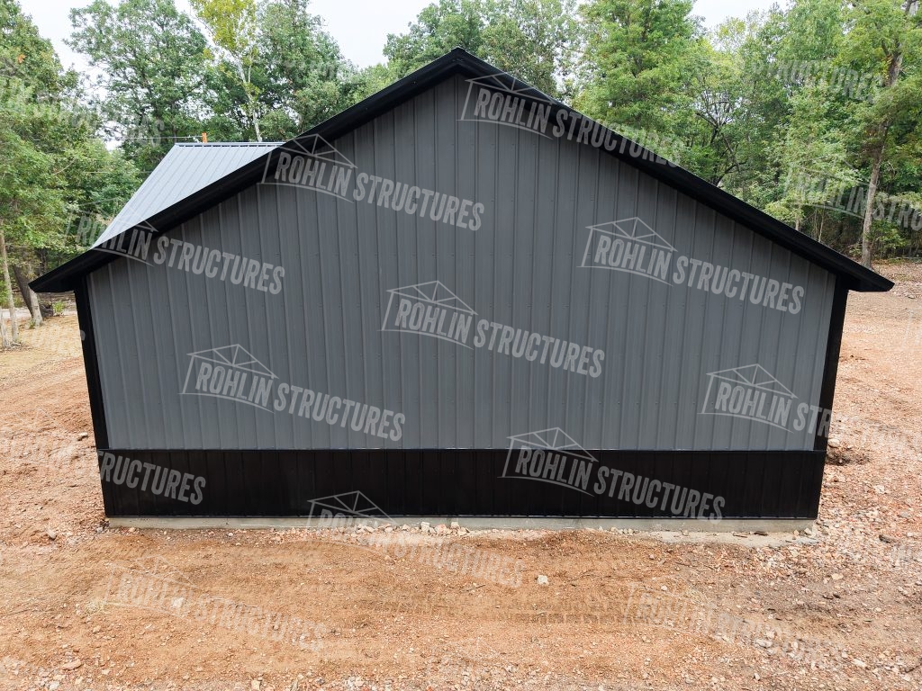 Newly constructed Rohlin Structures pole barn with gray siding and black trim.