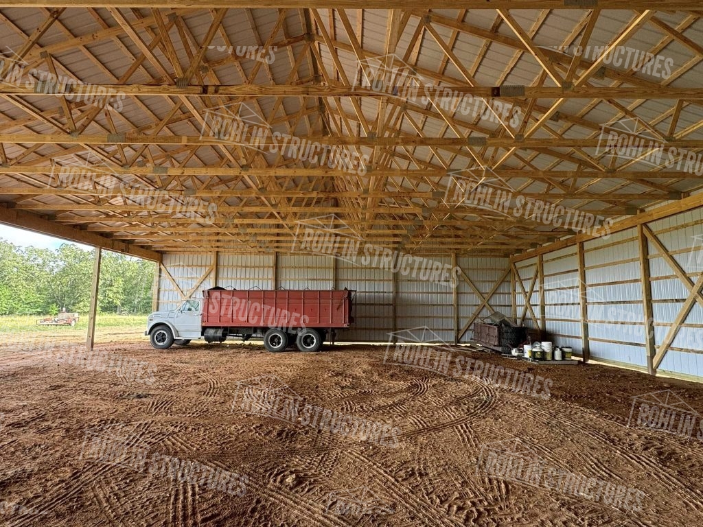 Interior view of a Rohlin Structures equipment cover featuring wood trusses, metal roofing, and siding.
