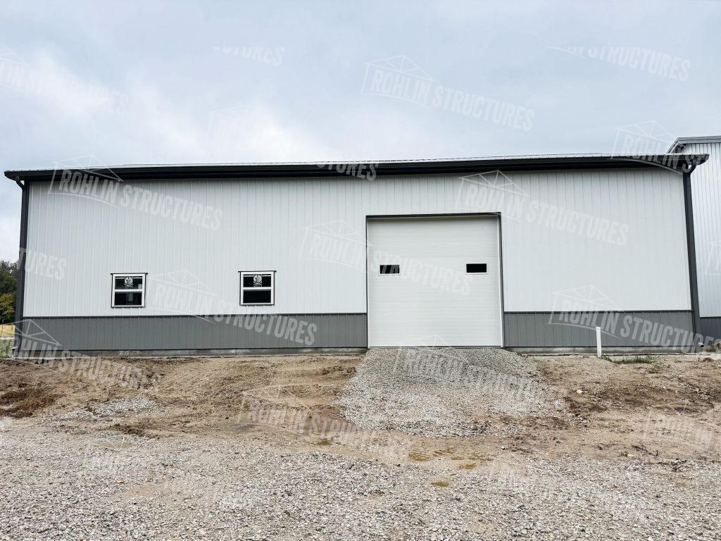 Custom pole barn building featuring metal siding and a white garage door built by Rohlin Structures.