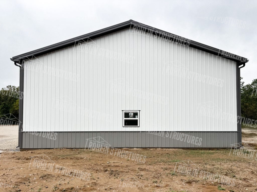 Custom white metal pole barn with dark trim and wainscoting built by Rohlin Structures.